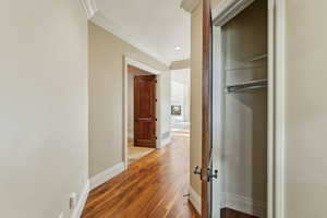 Corridor featuring ornamental molding, wood finished floors, and recessed lighting