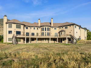 Rear view of property with stairs, a chimney, a wooden deck, and stucco siding