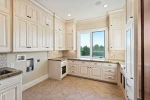 Laundry area with cabinet space, hookup for an electric dryer, crown molding, washer hookup, and light tile patterned floors