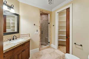Full bath featuring a stall shower, vanity, ornamental molding, and a spacious closet