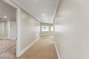 Corridor featuring light colored carpet, crown molding, recessed lighting, and attic access