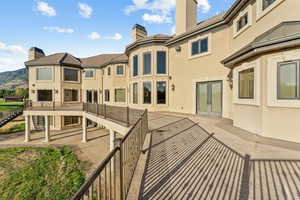 Rear view of property featuring stairs, a chimney, stucco siding, a patio area, and french doors