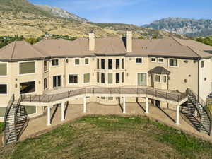 Rear view of house with stairway, a chimney, stucco siding, and a patio area