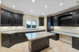 Kitchen featuring crown molding, open shelves, a kitchen island, recessed lighting, and built in desk