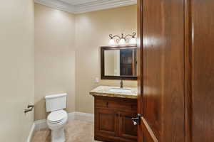 Half bathroom with vanity and crown molding