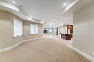 Unfurnished living room with ornamental molding, light carpet, recessed lighting, and a brick fireplace
