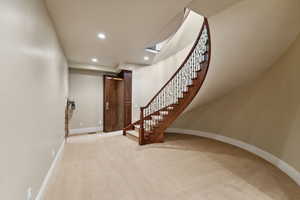 Carpeted foyer entrance with recessed lighting and stairs