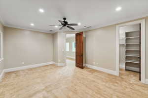 Unfurnished bedroom featuring light colored carpet, crown molding, a spacious closet, recessed lighting, and ceiling fan