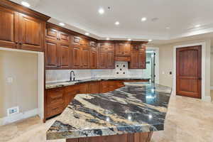 Kitchen with tasteful backsplash, ornamental molding, recessed lighting, dark stone countertops, and stovetop