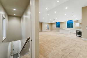 Unfurnished living room with light colored carpet, recessed lighting, and a high ceiling