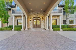 Entrance to property with a balcony, french doors, and stone siding
