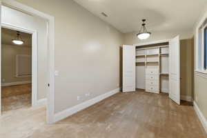 Unfurnished bedroom with light carpet, a closet, and vaulted ceiling