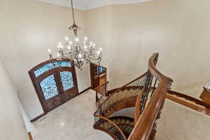 Foyer with a chandelier, french doors, stairway, a towering ceiling, and crown molding