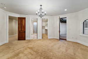 Unfurnished bedroom with recessed lighting, ornamental molding, carpet, a spacious closet, and a chandelier