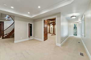 Empty room with light carpet, recessed lighting, a raised ceiling, crown molding, and stairway