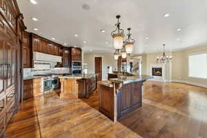 Kitchen with a breakfast bar, a spacious island, crown molding, recessed lighting, and hardwood / wood-style flooring
