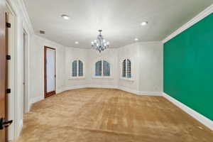 Unfurnished dining area with ornamental molding, carpet flooring, a chandelier, and recessed lighting