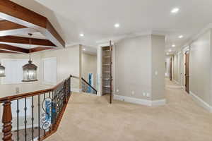 Hallway featuring an upstairs landing, light colored carpet, recessed lighting, and ornamental molding
