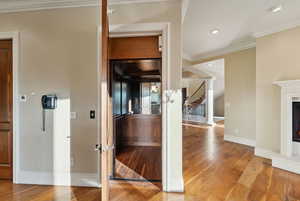 Kitchen with decorative columns, crown molding, hardwood / wood-style floors, arched walkways, and recessed lighting