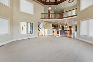Unfurnished living room with plenty of natural light, ornamental molding, stairs, light colored carpet, and recessed lighting