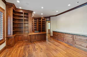 Unfurnished office featuring crown molding, built in study area, recessed lighting, and light wood finished floors