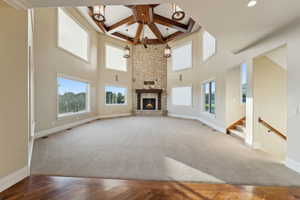 Unfurnished living room with carpet flooring, a fireplace, coffered ceiling, beam ceiling, and stairs