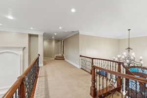 Hall featuring an upstairs landing, crown molding, carpet floors, a chandelier, and recessed lighting