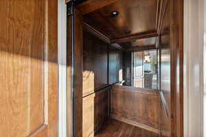 Elevator with wood finished floors, ornamental molding, and wood ceiling