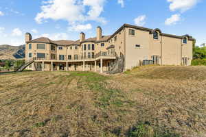Back of property featuring stairs, stucco siding, a chimney, and a lawn