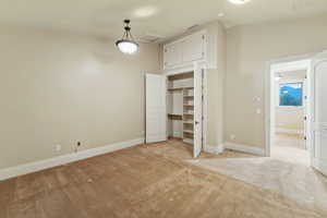 Unfurnished bedroom with light carpet and attic access