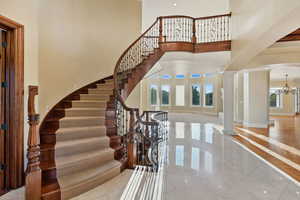 Foyer entrance with decorative columns, a chandelier, stairs, and a high ceiling