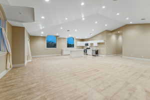 Unfurnished living room with recessed lighting, vaulted ceiling, and light carpet