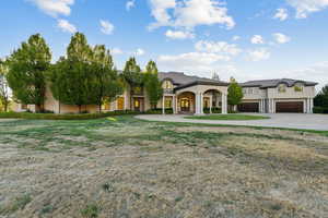 French provincial home featuring concrete driveway, stucco siding, and a front lawn