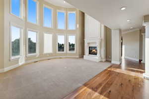 Unfurnished living room featuring crown molding, ornate columns, a large fireplace, light wood-style floors, and recessed lighting