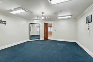 Unfurnished room featuring ornamental molding and dark colored carpet