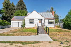 View of front of house featuring a metal roof, concrete driveway, a chimney, and a garage