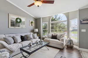 Living room featuring crown molding, vaulted ceiling, wood finished floors, and a ceiling fan