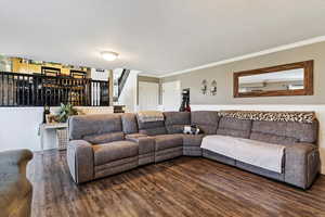 Living area with stairs, wood finished floors, and ornamental molding