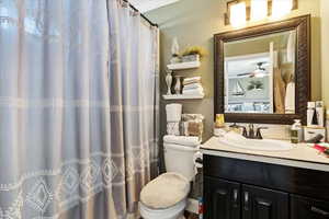 Bathroom with vanity, a ceiling fan, and a shower with curtain