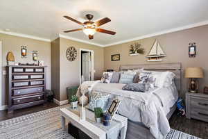 Bedroom with crown molding, dark wood-type flooring, and a ceiling fan