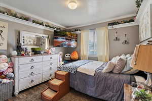 Bedroom with ornamental molding, dark wood-style flooring, and a textured ceiling
