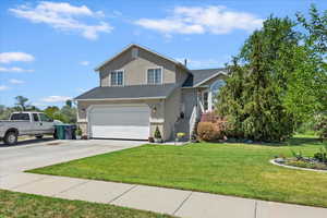 View of front facade with driveway, stucco siding, a garage, a front yard, and a shingled roof