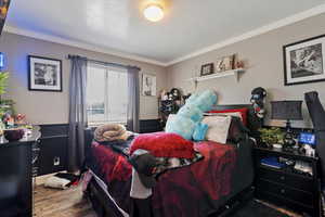 Bedroom with ornamental molding, wood finished floors, and a textured ceiling