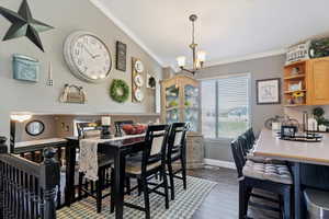 Dining area with a chandelier, dark wood-style floors, and crown molding