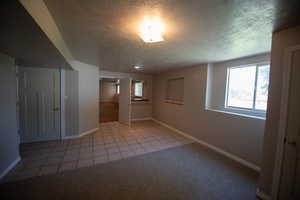 Empty room featuring healthy amount of natural light, a textured ceiling, and light tile patterned flooring