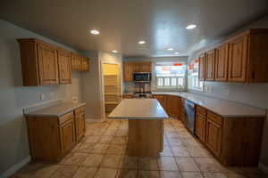 Kitchen with a center island, stainless steel appliances, recessed lighting, light countertops, and light tile patterned flooring