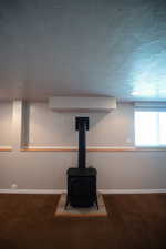 Detailed view of a textured ceiling, a wood stove, and carpet floors