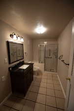 Full bathroom featuring a textured ceiling, a stall shower, tile patterned floors, and vanity