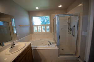 Bathroom with a tub with jets, vanity, a stall shower, tile patterned flooring, and recessed lighting