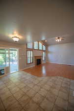 Unfurnished living room with plenty of natural light, light wood-style flooring, a fireplace, lofted ceiling, and ceiling fan
